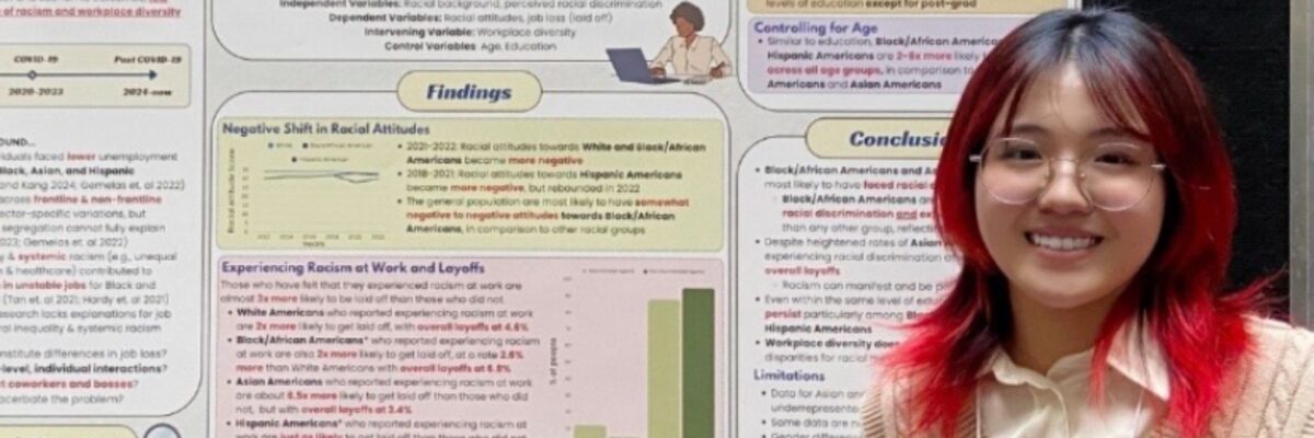 Intern Esta Lee stands in front of a multicoloured poster with research findings on race and job loss during COVID-19