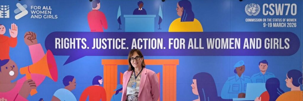 Abida Pehlic stands in front of a colourful backdrop with the CSW70 theme and graphics